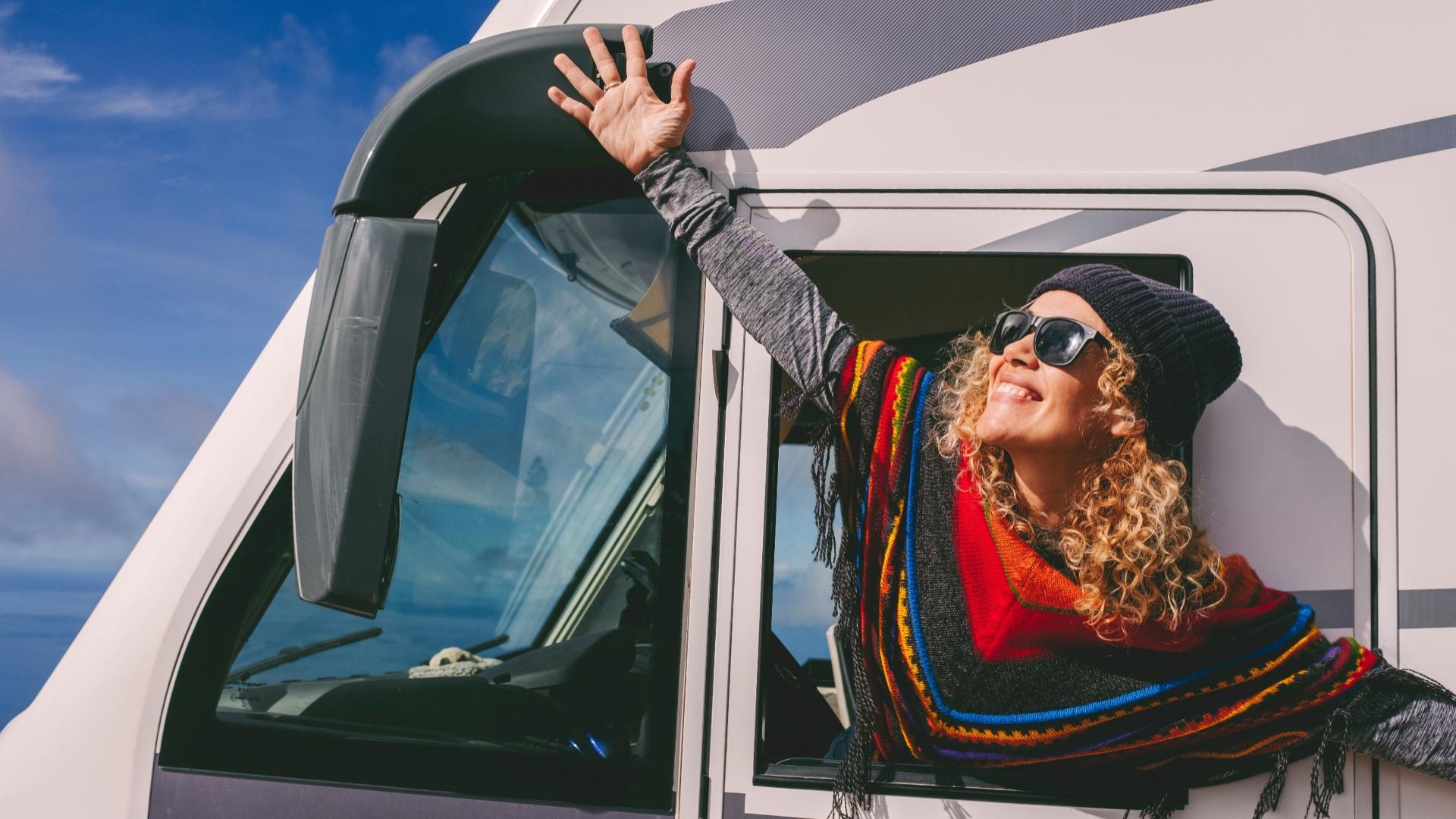 Donna felice che sorride fuori dal finestrino di un camper.