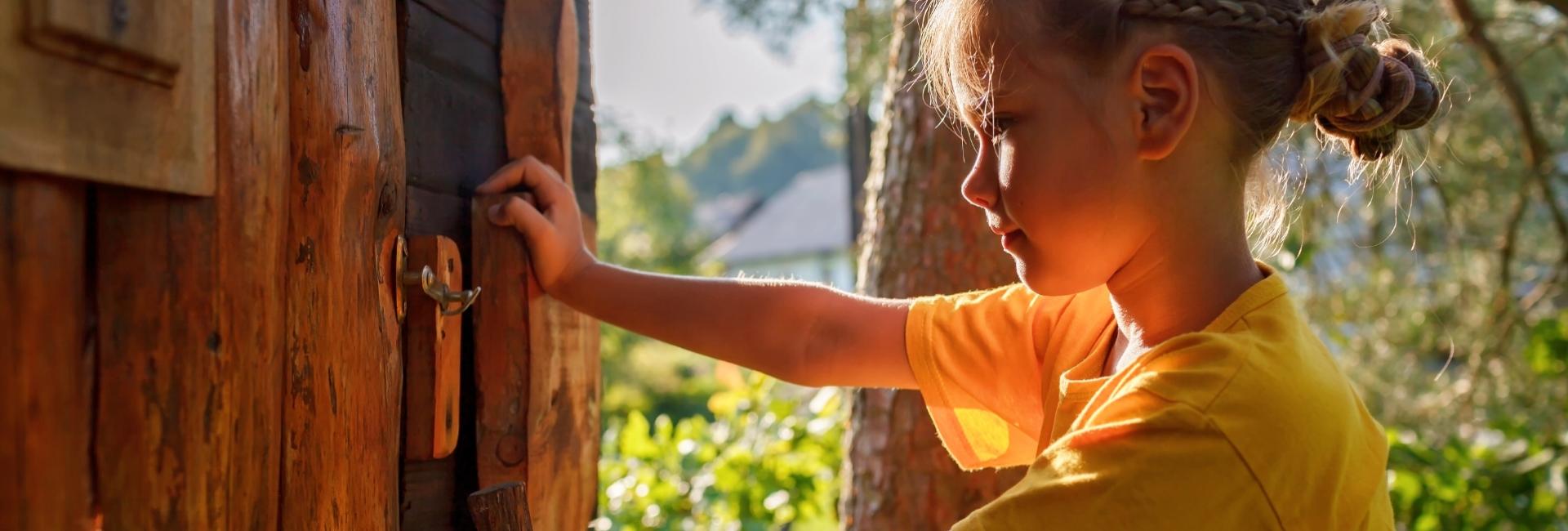 Bambina apre una porta di legno in una casa sull'albero.