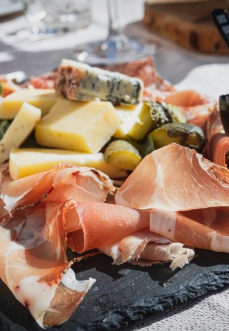 Plateau avec charcuterie, fromages, cornichons et une petite coupelle de crème.