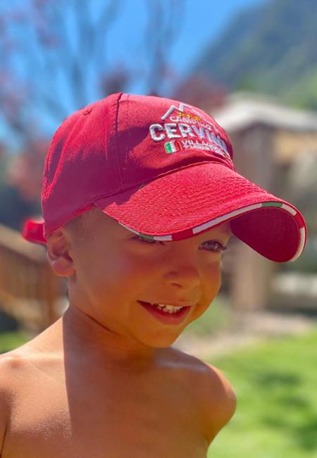 Bambino con cappello rosso, all'aperto in una giornata soleggiata.