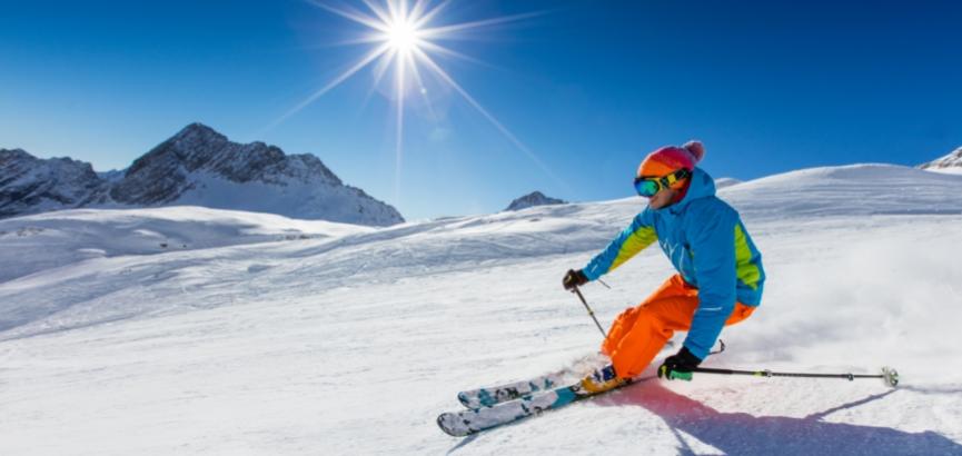 Sciare su una pista innevata sotto un cielo blu e sole splendente.