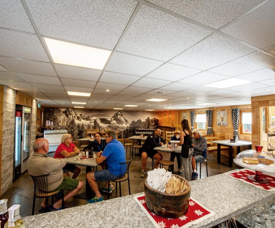 Persone che chiacchierano in una caffetteria con decorazioni in legno e foto di montagne.