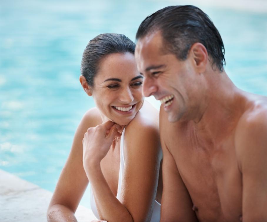 Coppia sorridente in piscina, godendosi un momento di relax.