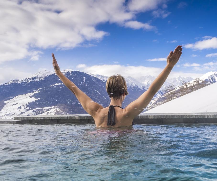 Persona in piscina con vista sulle montagne innevate.