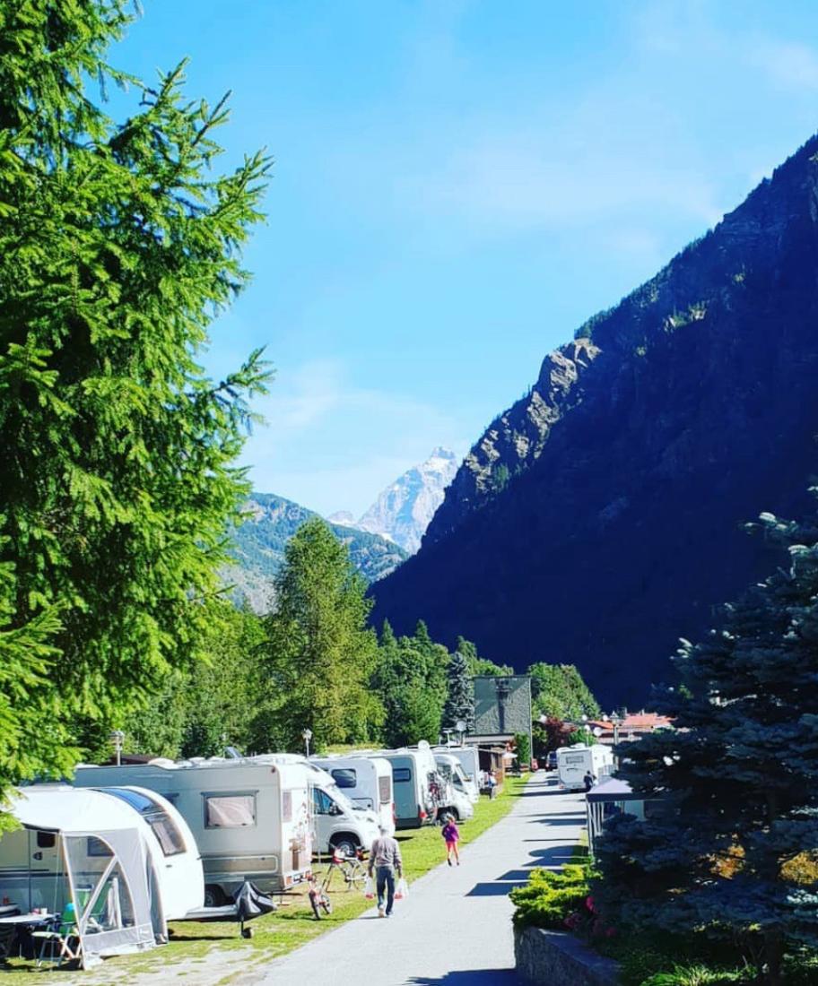 Campeggio tra le montagne con camper e caravan, giornata soleggiata.