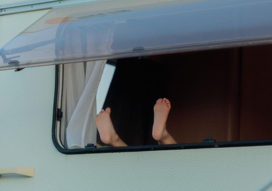 Piedi che sporgono da una finestra di un camper.