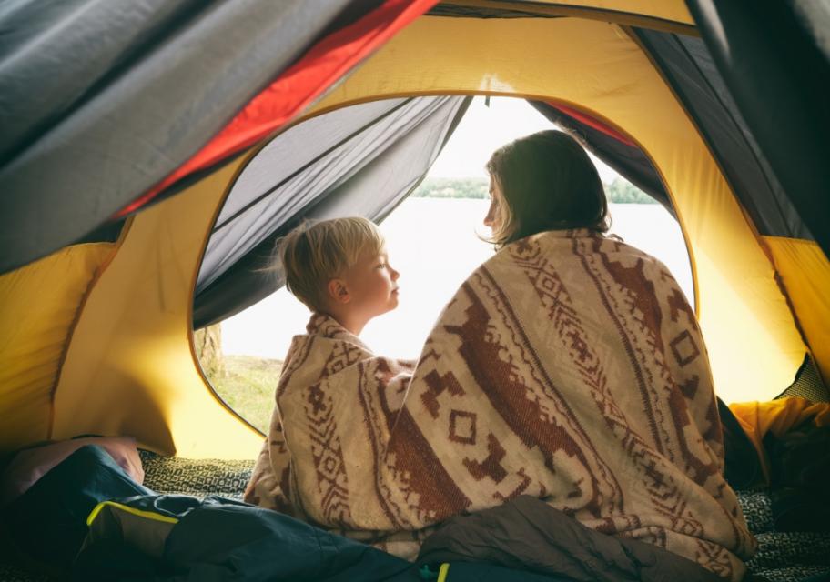 Deux personnes enveloppées dans une couverture à l'intérieur d'une tente de camping.