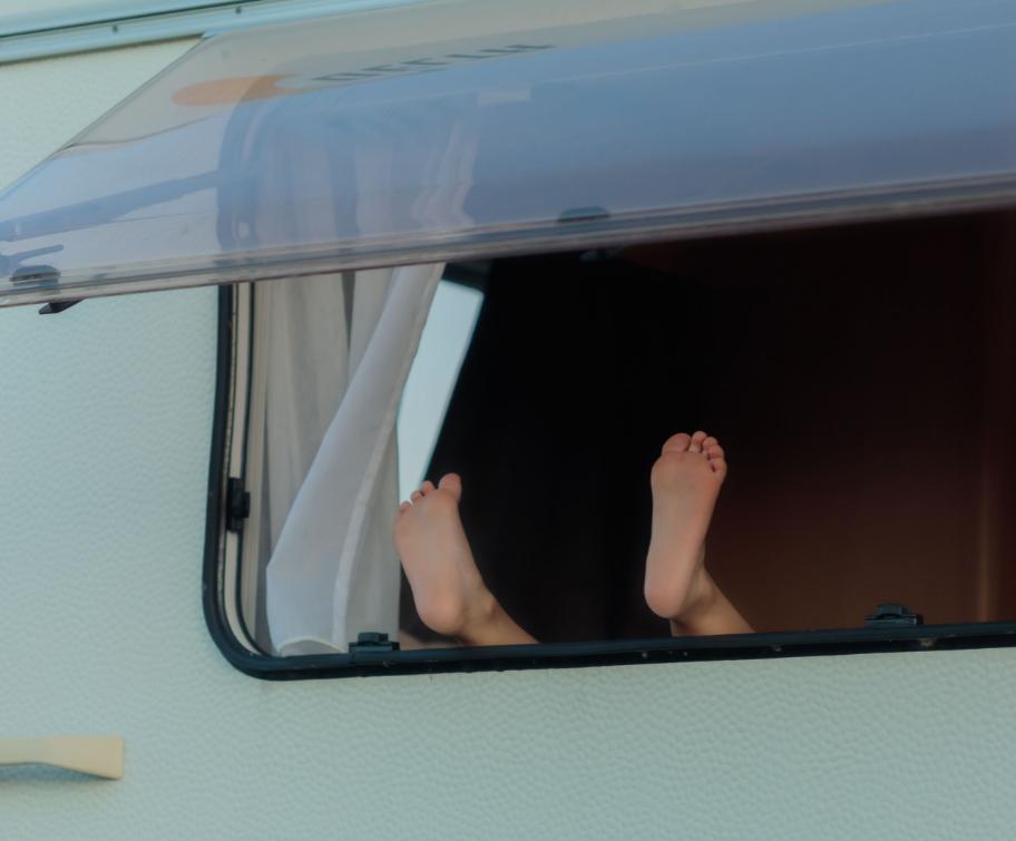 Piedi che sporgono da una finestra di un camper.